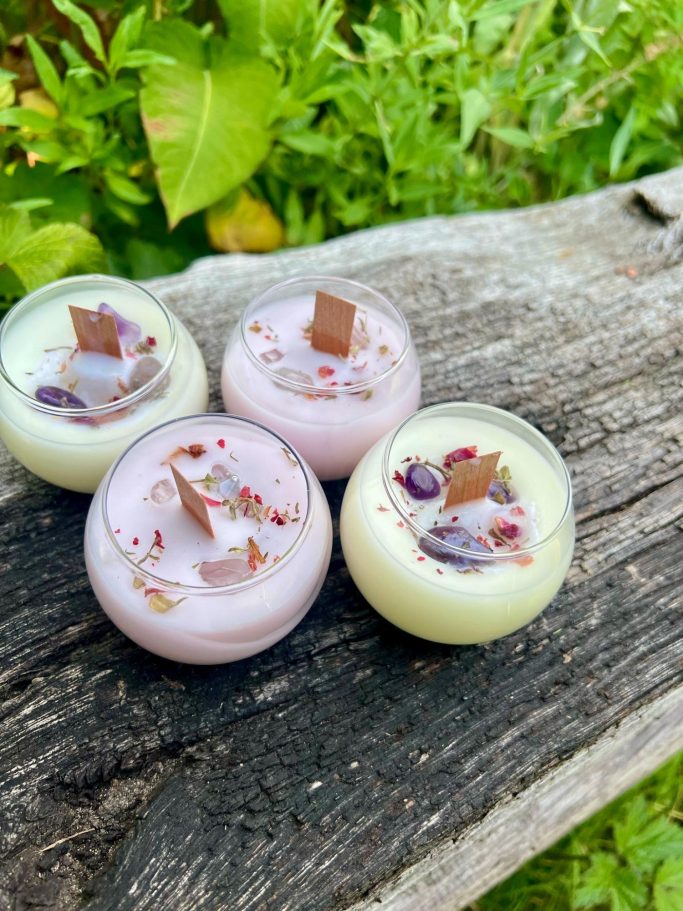 Drei kleine Gläser mit buntem Pudding, dekoriert mit Schokolade und Blütenblättern.