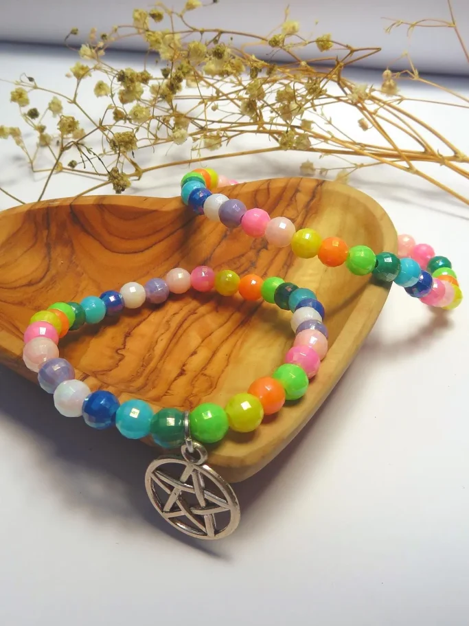 Bunte Perlenarmbänder mit einem pentagrammförmigen Anhänger auf einem Holzuntergrund.