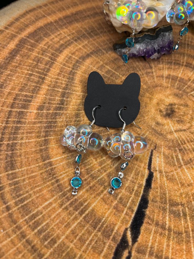 Silberne Ohrhänger mit bunten Glaskugeln und türkisfarbenen Anhängern auf einem Holzuntergrund.